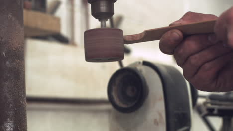 Gleitender-Pull-Back-Schuss-Der-Hände-Eines-Arbeiters-Mit-Einer-Schleifmaschine,-Um-Ein-Stück-Holz-Zu-Formen