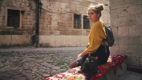 4K-UHD-Cinemagraph-of-a-young-brunette-woman-sitting-next-to-a-black-cat-in-the-famous-old-city-of-Kotor-in-Montenegro