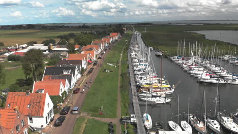 Aerial-tilt-showing-the-marine-port-area-for-pleasure-boats-and-sailboats-with-typical-houses-of-the-Dutch-village-of-Durgerdam-at-the-Durgerdammerdijk-near-Amsterdam-against-a-blue-sky-with-clouds