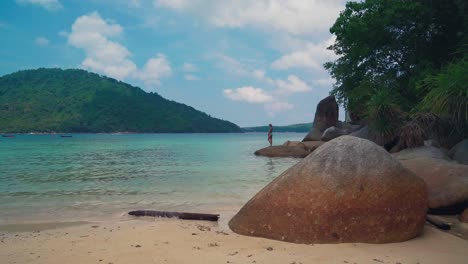 Ein-Wunderschöner-4K-UHD-Cinemagraph-Eines-Tropischen-Küstenstrandes-Auf-Der-Insel-Perhentian,-Malaysia,-Und-Ein-Brünettes-Model-Auf-Einem-Felsen