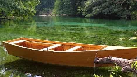 Wooden-small-boat-floating-on-the-surface-of-a-calm-pristine-crystal-clear-reflective-water