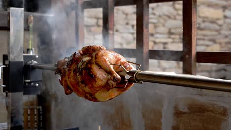 Roasting-trussed-chickens-on-rotisserie-spit-over-open-smoky-wood-fired-bbq