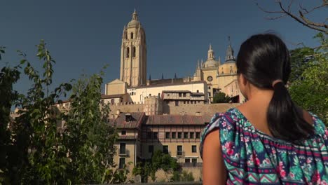 Slow-push-in-towards-back-of-female,-standing,-looking-at-Segovia-townscape-from-distance-SLOW-MOTION