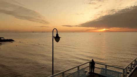 Das-Mädchen-Steht-Auf-Einem-Pier-Und-Fotografiert-Mit-Ihrem-Handy-Die-Aufgehende-Sonne