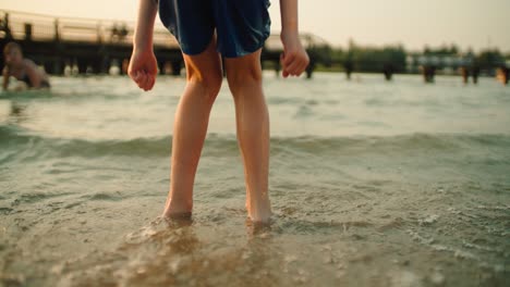 Back-view-of-the-boy's-legs-are-jumping-through-the-waves