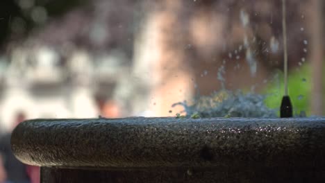 Close-up-view-of-water-fountain-spitting-out-water-with-blurred-bokeh-background-in-park-setting