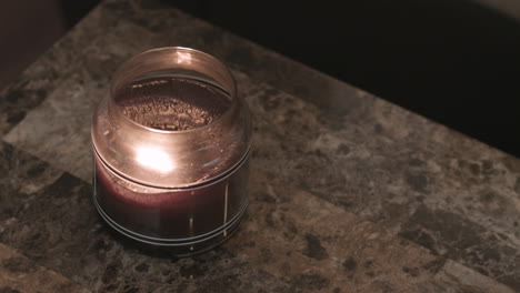 Still-shot-of-a-scented-candle-burning-on-a-modern-granite-tabletop