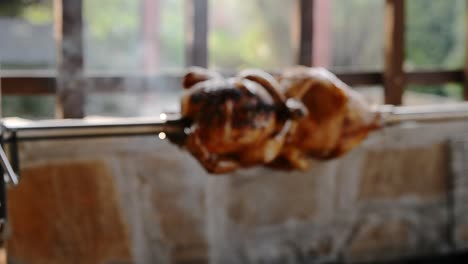 Roasting-trussed-chickens-on-rotisserie-spit-over-open-smoky-wood-fired-bbq