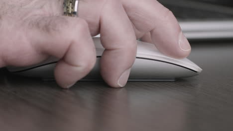 Macro-shot-of-executive-hand-using-a-mouse-next-to-his-laptop-computer