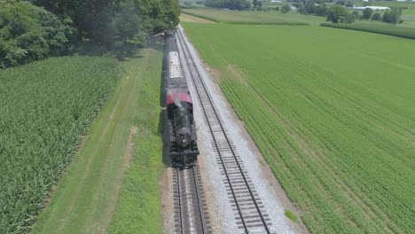 Aerial-View-of-a-1910-Steam-Engine-with-Passenger-Train-Puffing-Smoke-Traveling-Along-the-Amish-Countryside-on-a-Sunny-Summer-Day-as-Seen-by-a-Drone