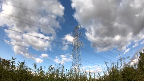 Time-Lapse-of-a-National-Grid-electricity-power-pylon-in-a-rural-location-with-blue-sky-and-wind-clouds-passing-by,-England,-UK