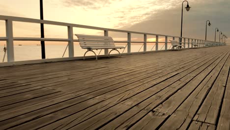 Aerial-footage-boards-and-benches-on-the-pier-at-sunrise-at-the-seaside