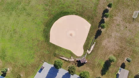High-aerial-rotating-shot-of-empty-baseball-field,-no-people,-in-rural-countryside-in-summer,-home-of-little-league