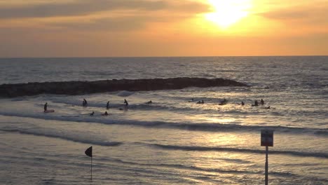 Silhouettes-of-surfers-in-the-Mediterranean-sea-in-Tel-Aviv,-Israel