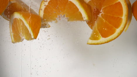Orangenkeile-In-Zeitlupe,-Die-In-Wasser-Fallen,-Erfrischende-Orange,-Die-In-Weißen-Hintergrund-Des-Wassers-Fällt