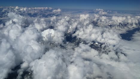 Aerial-mountain-view-of-snowy-andes-summit-above-clouds,-south-america