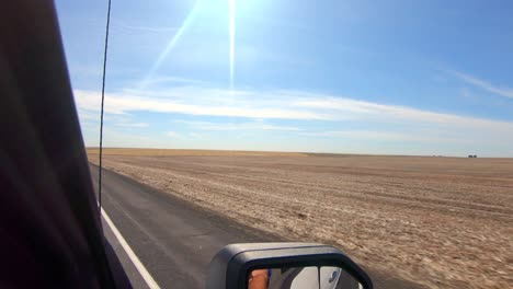 POV-out-of-the-passenger's-side-window-while-driving-past-harvested-wheat-fields-in-an-agricultural-area-of-Eastern-Washington-State