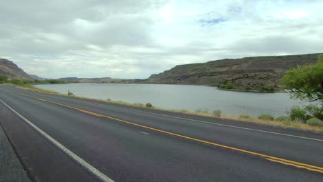 POV-of-the-passenger-of-a-parked-Class-A-RV,-point-of-view-of-Blue-Lake-and-traffic-on-Highway-17-in-Washington-State-on-a-cloudy,-windy-day