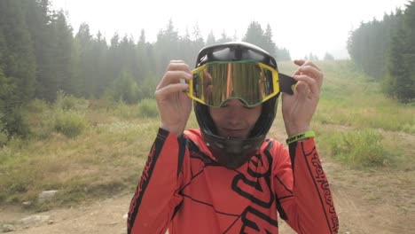 portrait-close-up-of-athlete---downhill-bike-rider-putting-on-his-goggles-wearing-a-full-face-helmet