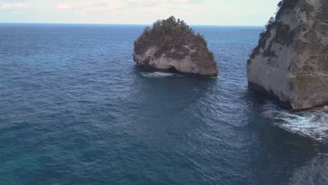 Luftaufnahme-Des-Kristallblauen-Wassers-Von-Diamond-Beach-In-Nusa-Penida,-Indonesien-Mit-Einer-Markanten-Großen-Klippe-Im-Vordergrund