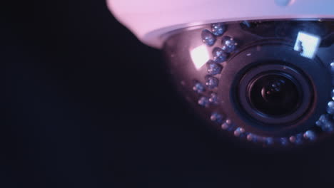Close-up-detail-shot-of-security-camera-sliding-in-and-out-of-frame-on-dark-background