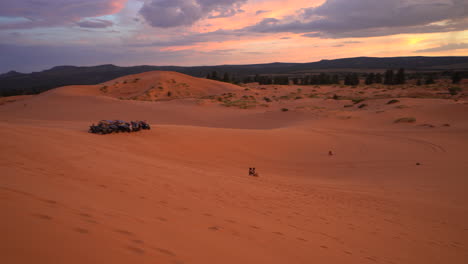 Two-People-Sand-Boarding-Down-The-Pink-Sand-Dunes-During-Sunset