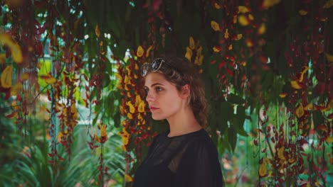 4K-UHD-Cinemagraph-of-a-young-brunette-woman-standing-next-to-a-beautiful-colorful-tree-with-a-lot-of-flower-blossoms-moving-around-her-head