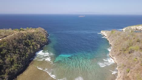 Vista-Aérea-De-La-Playa-De-Atuh-En-Nusa-Penida,-Indonesia-En-Un-Día-Soleado-Y-Con-Agua-Azul-Cristalina-Golpeando-Las-Formaciones-Rocosas