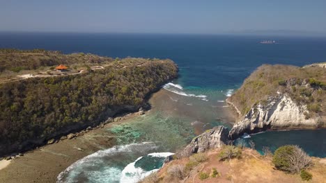 Vista-Aérea-De-La-Playa-De-Atuh-En-Nusa-Penida,-Indonesia-En-Un-Día-Soleado-Y-Con-Agua-Azul-Cristalina-Golpeando-Las-Formaciones-Rocosas