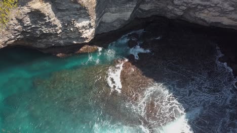Aerial-view-of-the-crystal-blue-water-of-broken-bay-in-Nusa-Penida,-Indonesia-with-the-waves-hitting-the-cliffs