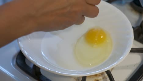 Rompiendo-Huevos-En-Un-Tazón-Blanco-En-La-Estufa,-Cámara-Lenta