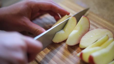 Slow-motion-shot-of-someone-using-a-knife-to-cut-a-ripe-apple-into-small-slices