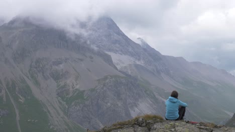 A-lone-female-hiker-looks-out-over-some-high-alpine-mountains-and-valley