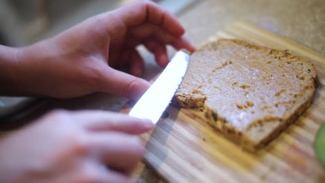 Slow-Motion-shot-of-someone-spreading-Peanut-Butter-onto-a-piece-of-whole-wheat-bread-toast