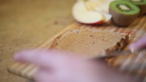 Slow-Motion-shot-of-someone-spreading-Peanut-Butter-onto-a-piece-of-whole-wheat-bread-toast