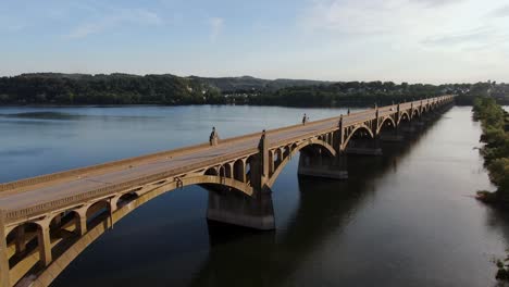 Reverse-aerial-wide-angle-drone-shot-of-traffic-crossing-bridge-above-Susquehanna-River-between-Columbia-and-Wrightsville,-Pennsylvania,-USA