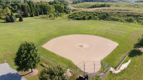 Aufsteigende-Antenne-Des-Baseballdiamanten-In-Der-Ländlichen-Landschaft,-Bäume-Und-Felder-In-Der-Ferne