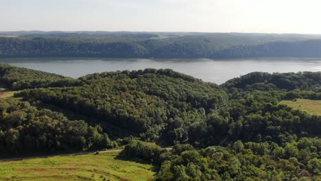 High-aerial-dolly-shot-drone-flying-above-trees-toward-mighty-Susquehanna-River-in-Pennsylvania,-summer-afternoon-shot