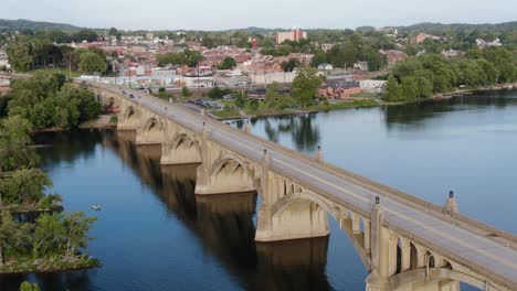 Slow-aerial-pull-back-shot-above-Susquehanna-River-long-concrete-arched-bridge-with-Columbia-Borough,-Pennsylvania-in-distance