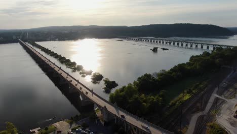 Aerial-descending-drone-shot-of-Veterans-Memorial-Bridge-Route-462-at-sunset-with-Route-30-in-distance,-York-County-Pennsylvania-on-horizon