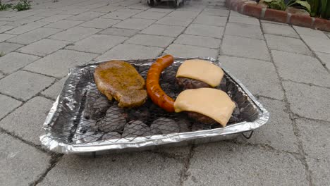 Locked-off-view-of-disposable-mini-BBQ-grill-with-different-and-cheesburger-on-tile-floor