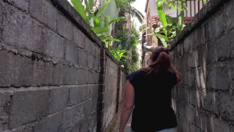 Mujer-Caucásica-Blanca-Caminando-Por-Un-Callejón-Estrecho-En-La-Ciudad-Tropical-De-Ubud,-Bali-Explorando-La-Zona,-Turista