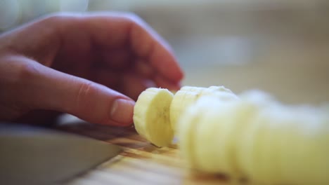 Slow-motion-shot-of-someone-using-a-knife-to-cut-a-ripe-yellow-banana-into-small-slices