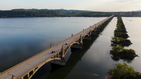 Dolly-forward-drone-shot-of-Susquehanna-River-at-sunset-with-traffic,-old-bridge-piers-remain-after-bridge-burned-in-US-Civil-War