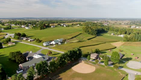 Descending-aerial-of-farmland-in-Washington-Boro-Lancaster-County,-green-farmland-in-summer,-baseball-diamond,-fields