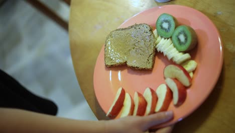Slow-Motion-shot-of-someone-setting-a-plate-full-of-breakfast-food-on-a-wooden-table