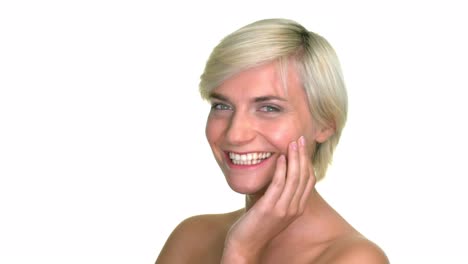 Close-up-shot-of-a-blonde,-short-haired-woman,-smile-and-resting-her-hand-upon-her-face-in-a-studio-with-a-seamless-white-background