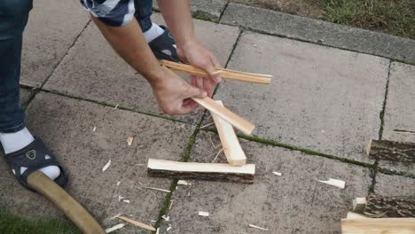 Young-man-is-chopping-wood-in-smaller-pieces-and-putting-it-aside
