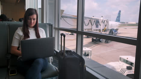 Attractive-young-woman-uses-laptop-in-airport-terminal