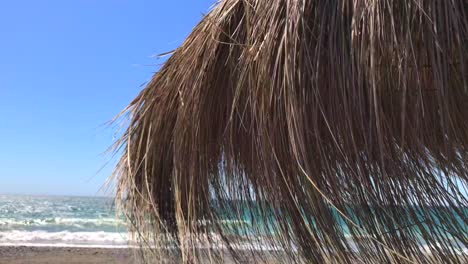 Windy-day-at-the-beach-with-a-thatch-umbrella-in-Marbella-Malaga-Spain
